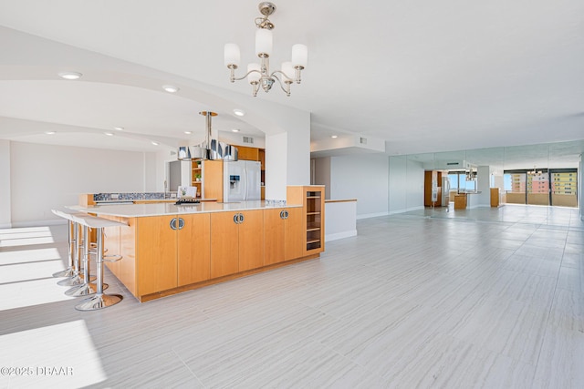 kitchen featuring pendant lighting, white refrigerator with ice dispenser, and a notable chandelier