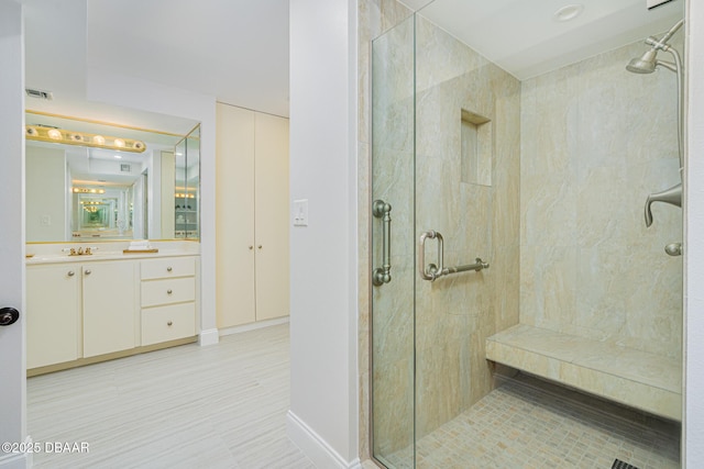 bathroom featuring a shower with door and vanity