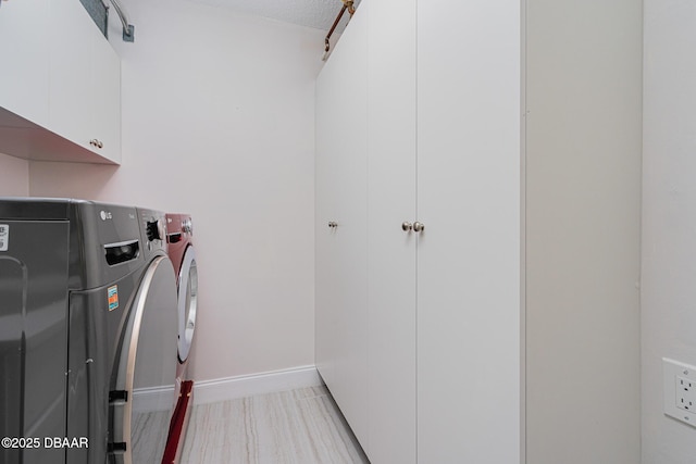 clothes washing area with cabinets, separate washer and dryer, and a textured ceiling