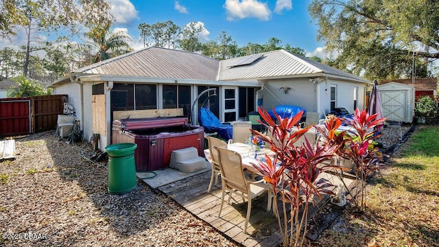 rear view of house with a hot tub, a sunroom, and a shed