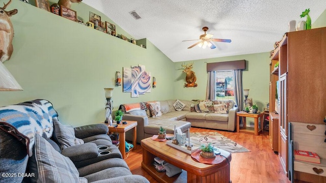 living room with ceiling fan, a textured ceiling, light hardwood / wood-style flooring, and lofted ceiling