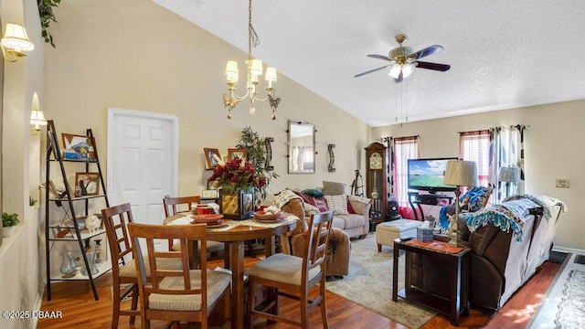 dining area featuring wood-type flooring, vaulted ceiling, ceiling fan with notable chandelier, and a textured ceiling