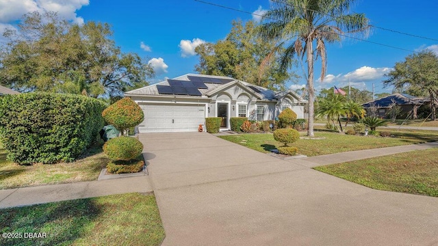 ranch-style house with a front yard, solar panels, and a garage