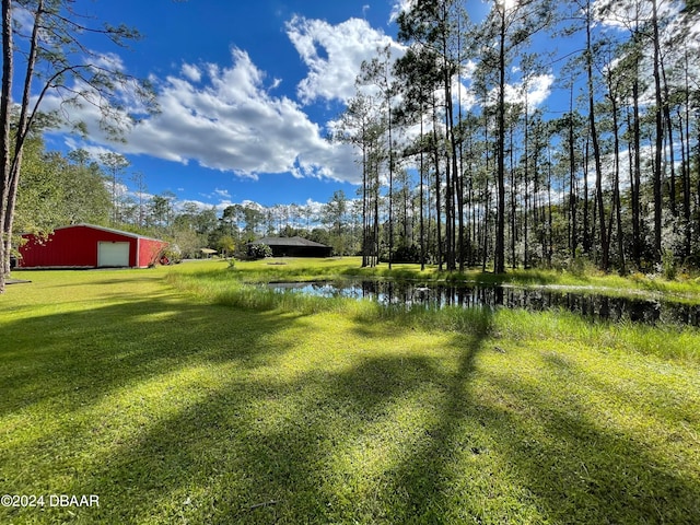 view of yard featuring an outbuilding, a garage, and a water view