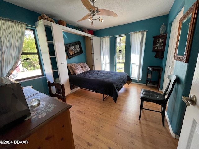 bedroom with ceiling fan, a textured ceiling, and light hardwood / wood-style flooring