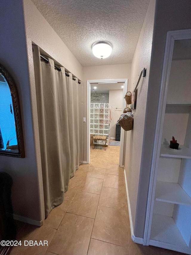 hallway featuring a textured ceiling and light tile patterned floors