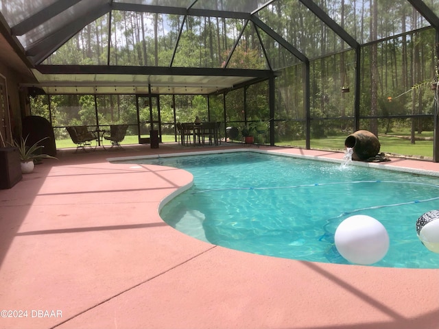 view of swimming pool with glass enclosure, pool water feature, and a patio area