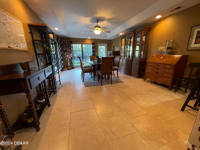 tiled dining space featuring a tray ceiling and ceiling fan