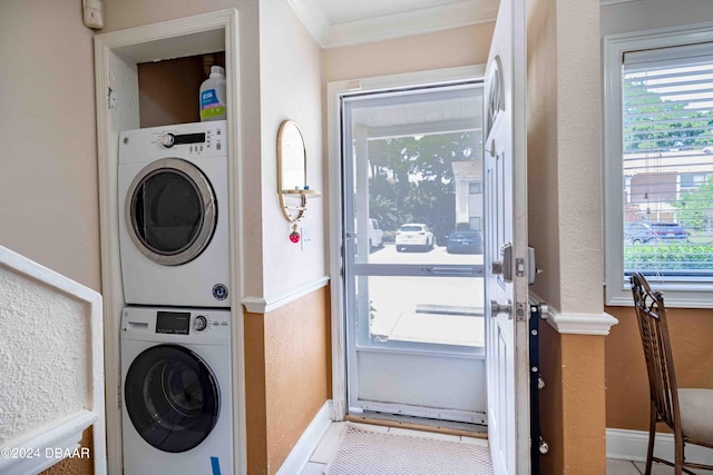 laundry area with stacked washer / dryer, light tile patterned floors, and ornamental molding