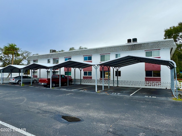 townhome / multi-family property with covered parking, mansard roof, and a shingled roof