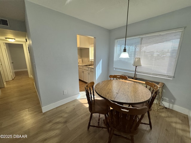 dining area featuring light wood-style floors, baseboards, and visible vents