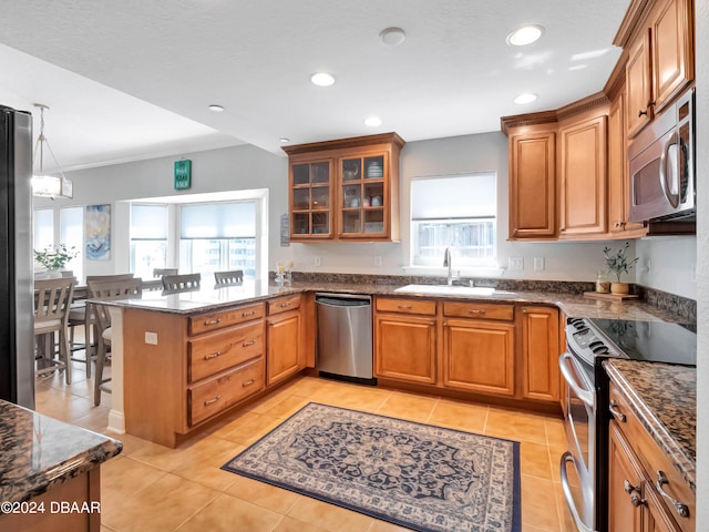 701 N Atlantic Ave Unit 202, New Smyrna Beach, FL 32169 - kitchen featuring stainless steel appliances, a sink, a peninsula, brown cabinetry, and light tile patterned floors