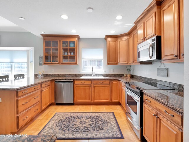 701 N Atlantic Ave Unit 202, New Smyrna Beach, FL 32169 - kitchen featuring stainless steel appliances, a sink, a peninsula, dark stone countertops, and glass insert cabinets