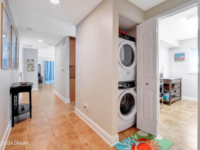 clothes washing area featuring light tile patterned floors and stacked washing maching and dryer