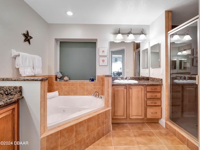 701 N Atlantic Ave Unit 202, New Smyrna Beach, FL 32169 - bathroom featuring two vanities, tile patterned flooring, a whirlpool tub, and a stall shower