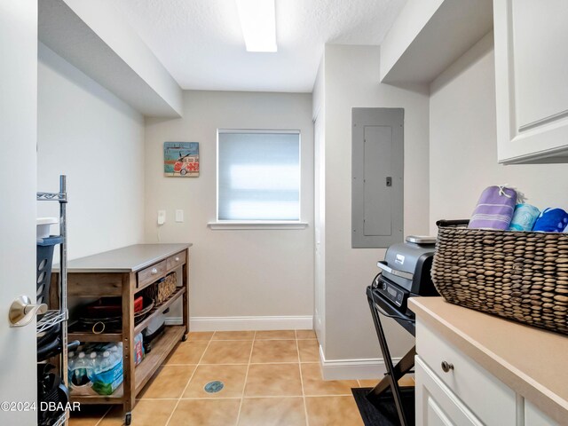 701 N Atlantic Ave Unit 202, New Smyrna Beach, FL 32169 - kitchen with electric panel, white cabinetry, light tile patterned floors, light countertops, and baseboards