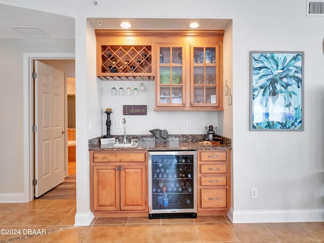 bar featuring light tile patterned flooring, sink, beverage cooler, and dark stone countertops