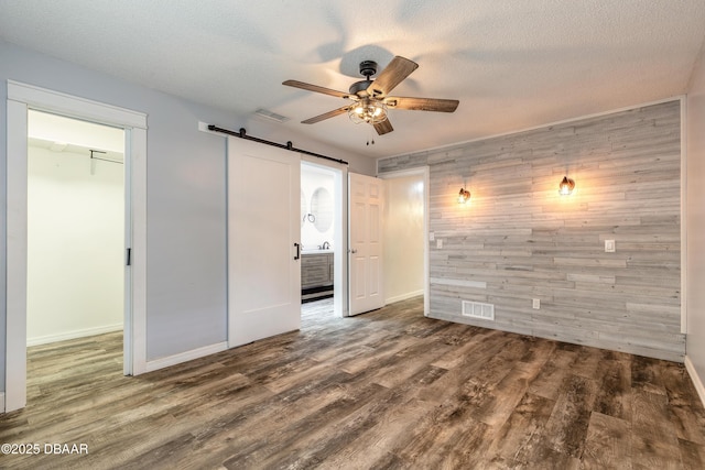 3643 Scott St, Port Orange, FL 32129 - unfurnished bedroom featuring wooden walls, a barn door, wood finished floors, ceiling fan, and a textured ceiling