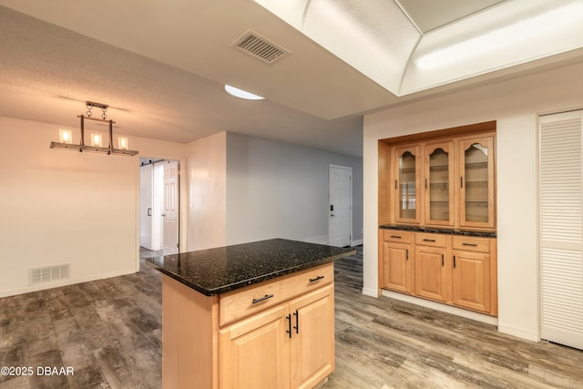 3643 Scott St, Port Orange, FL 32129 - kitchen with dark wood-style floors, dark stone countertops, a kitchen island, decorative light fixtures, and glass insert cabinets