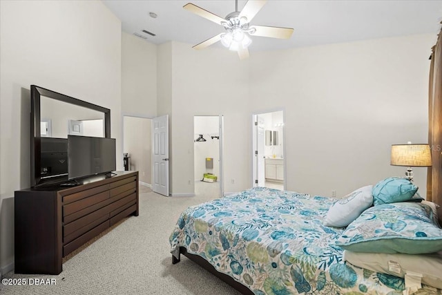 bedroom featuring light carpet, visible vents, baseboards, a towering ceiling, and ensuite bath