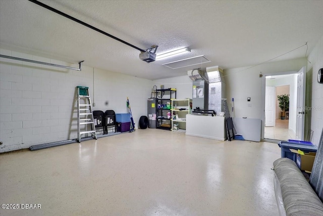 garage featuring concrete block wall, electric water heater, and a garage door opener