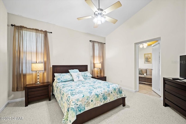 bedroom featuring light colored carpet, a ceiling fan, vaulted ceiling, ensuite bath, and baseboards