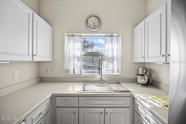 kitchen featuring light countertops, a sink, and white cabinets