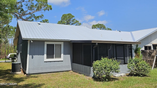 rear view of house with cooling unit, a yard, and a sunroom