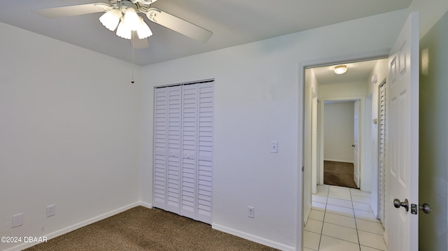 unfurnished bedroom featuring light carpet, a closet, and ceiling fan