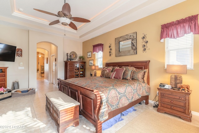 bedroom with ceiling fan, a raised ceiling, ornamental molding, and light tile patterned floors