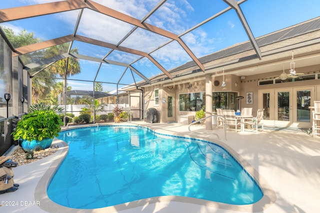 view of swimming pool featuring glass enclosure, ceiling fan, french doors, and a patio