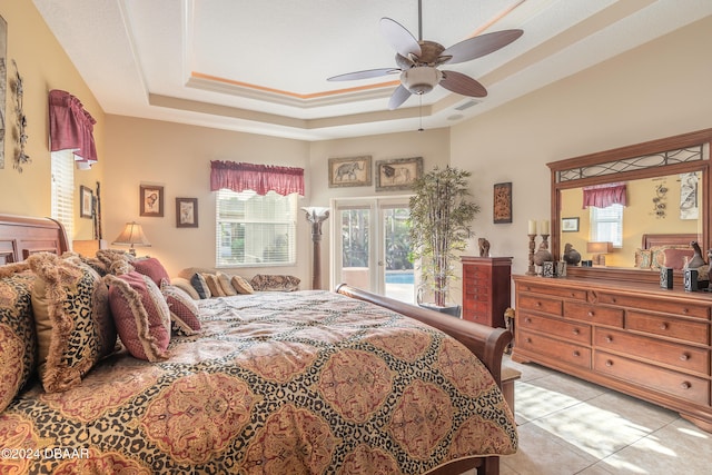 tiled bedroom with french doors, a raised ceiling, multiple windows, and ceiling fan