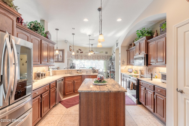 kitchen with ceiling fan, tasteful backsplash, decorative light fixtures, a kitchen island, and appliances with stainless steel finishes