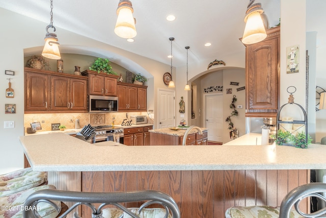 kitchen with kitchen peninsula, backsplash, stainless steel appliances, decorative light fixtures, and lofted ceiling