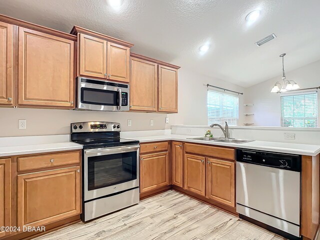 kitchen featuring stainless steel appliances, sink, lofted ceiling, light wood-type flooring, and a notable chandelier