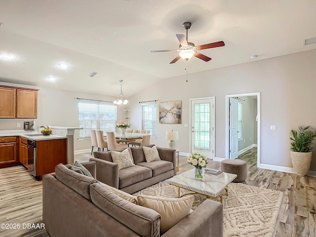 living room featuring lofted ceiling, ceiling fan with notable chandelier, light wood-type flooring, and sink