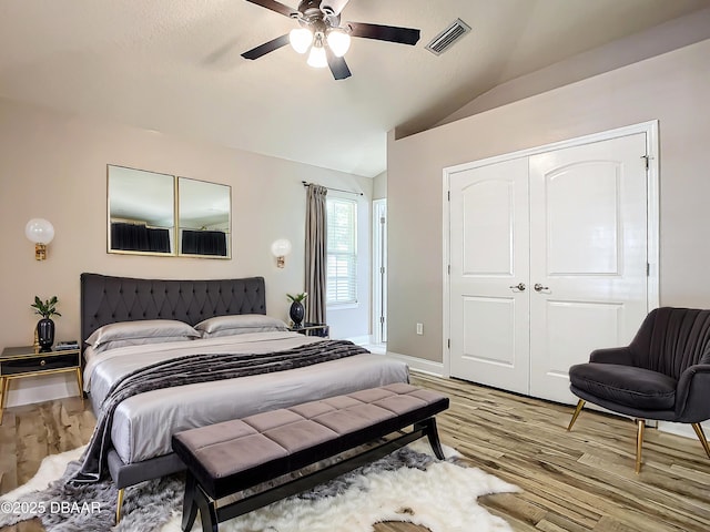 bedroom featuring vaulted ceiling, light wood-type flooring, ceiling fan, and a closet