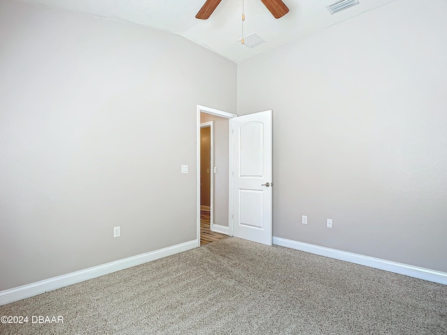 carpeted spare room featuring ceiling fan and vaulted ceiling