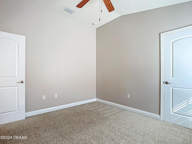 empty room featuring lofted ceiling, ceiling fan, and carpet flooring