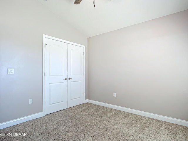 unfurnished bedroom featuring ceiling fan, a closet, carpet, and vaulted ceiling