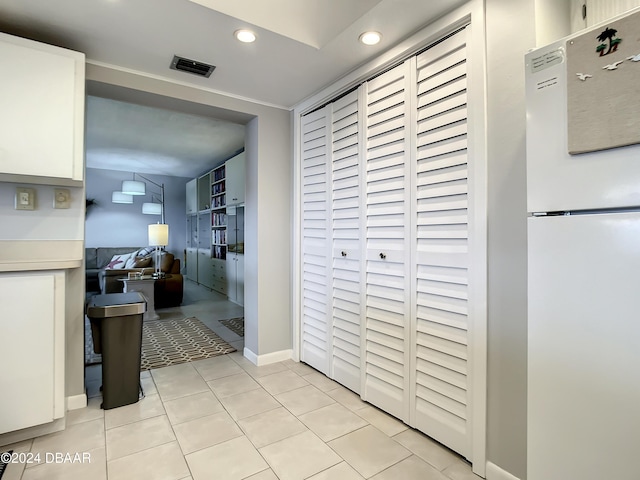 kitchen with white cabinets, light tile patterned floors, and white fridge