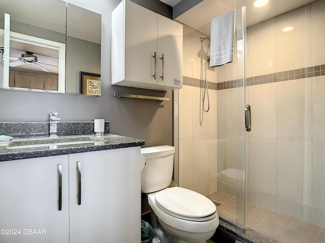 bathroom featuring vanity, toilet, ceiling fan, and a shower with shower door