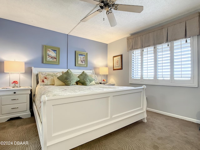 bedroom with ceiling fan, dark carpet, and a textured ceiling