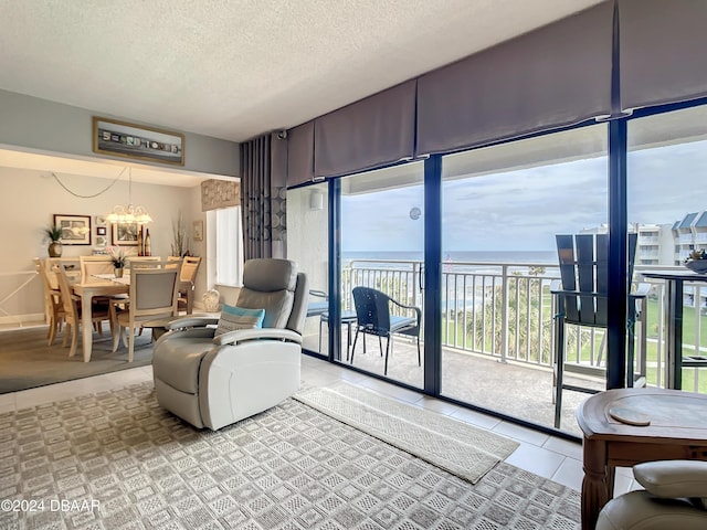 living room with a water view, light tile patterned floors, a textured ceiling, and a chandelier