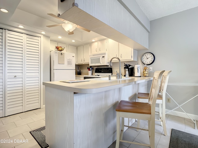 kitchen featuring kitchen peninsula, white cabinetry, light tile patterned flooring, and white appliances