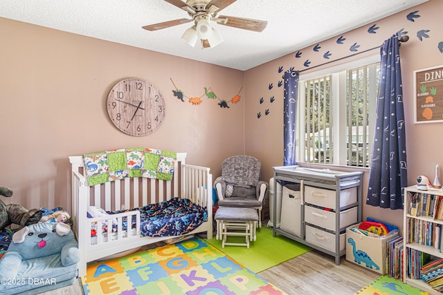 1724 Umbrella Tree Dr, Edgewater, FL 32132 - bedroom featuring wood finished floors, a textured ceiling, a ceiling fan, and a crib