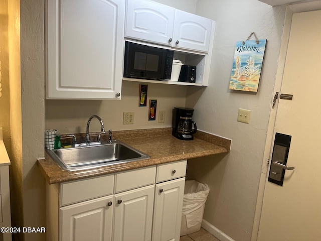 kitchen with white cabinets, tile patterned flooring, and sink