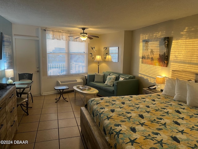 tiled bedroom featuring a wall mounted air conditioner, ceiling fan, and a textured ceiling