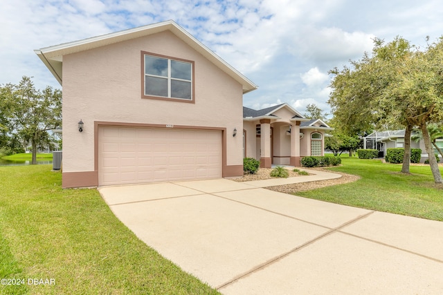 view of front of home with a garage, cooling unit, and a front yard