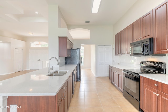 kitchen featuring sink, black appliances, light stone countertops, light tile patterned floors, and decorative backsplash